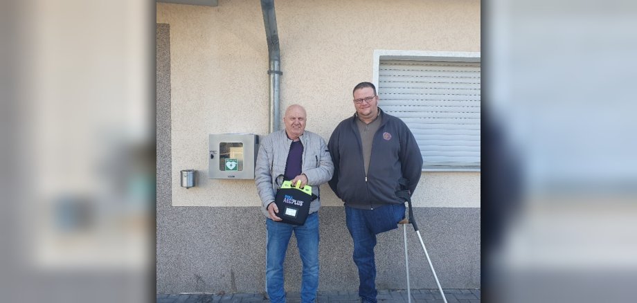 Zum Foto: Peter Pelk und Daniel Schmidt präsentieren den Defibrillator.