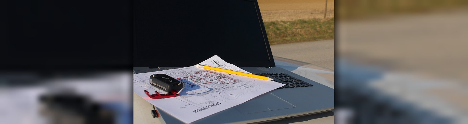 Zu sehen ist ein Bild mit einem Bauplan mit einem Laptop, was sinnbildlich für die Bauleitplanung stehen soll.